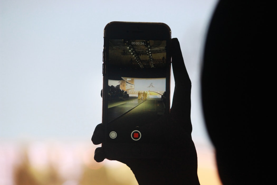 Osoba trzymająca w ręku telefon z włączonym nagrywanie wideo