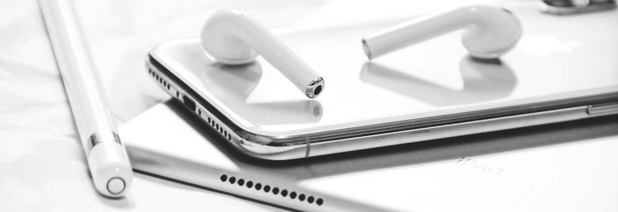 Słuchawki bezprzewodowe leżące na smartfonie i tablecie